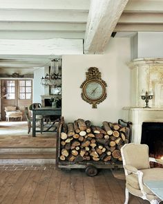 a living room filled with lots of firewood next to a clock on the wall