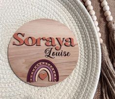 a wooden sign that says soraya house with a rainbow in the center and tassels around it