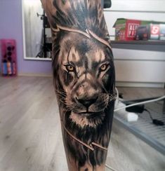 a man's leg with a lion tattoo on it and an arrow in the middle