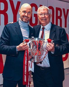 two men in suits holding up a trophy