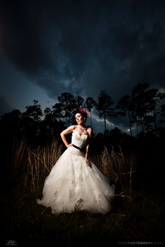 a woman in a white wedding dress standing in tall grass