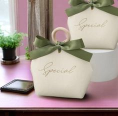 two white baskets with green bows are sitting on a table next to a cell phone