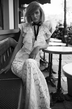 a woman is sitting on a bench wearing a dress