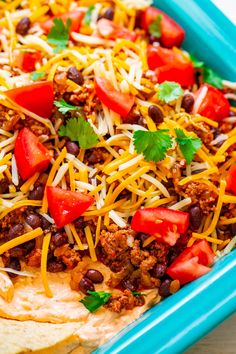 a blue dish filled with tortilla shells topped with cheese and black beans