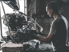 a man working on a motorcycle engine in a garage with lots of tools around him