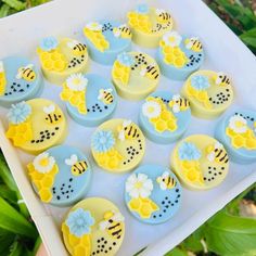 there are many decorated cupcakes in the shape of flowers and bees on display