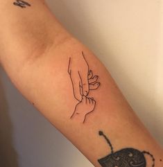 a tattoo on the arm of a person holding an elephant's hand with another hand