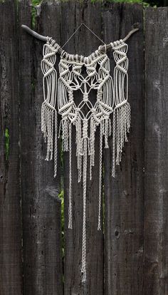 a white macrame hanging on a wooden fence