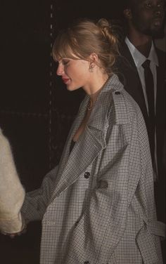 a woman in a trench coat is holding her hand out to another person who is wearing a suit and tie