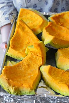 someone is holding a tray full of cut up avocado halves on tin foil