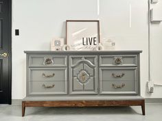 a grey dresser with gold handles and drawers