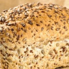 a loaf of bread sitting on top of a wooden cutting board with seeds all over it