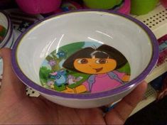 a hand holding a bowl with a cartoon character on the bottom and purple rims