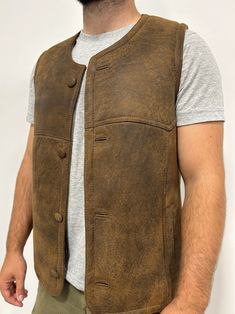 Perfect for three seasons, with the choice to layer on cooler days. Our sheepskin vest are durable, stylish and 100% natural allowing for your body to regulate warm in a productive way. Do you hate how body heat feels from polyester or synthetic fabrics? Then natural sheepskin and wool is the right choice for you. Our rancher vest is made from 100% leather and lined with 100% black mutton sheepskin. Our first model is wearing a size Large, is 6’ 5” and 175 pounds Our second model is wearing a si Rugged Leather Vest Outerwear, Rugged Brown Vest Outerwear, Rugged Fitted Vest Outerwear, Fitted Sleeveless Rugged Outerwear, Rugged Brown Winter Vest, Brown Rugged Winter Vest, Leather Winter Outdoor Vest, Brown Rugged Vest For Winter, Classic Brown Outdoor Vest