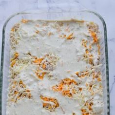 a casserole dish with carrots and cheese in it on a marble counter top