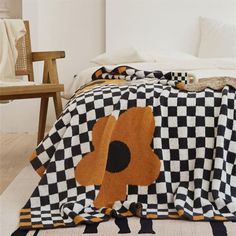 a black and white blanket with an orange flower on it