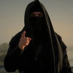 a person wearing a black burka giving the thumbs up sign