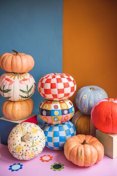 pumpkins and gourds are stacked on top of each other in front of a blue wall