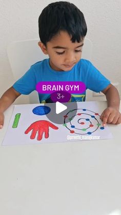 a little boy sitting at a table with a piece of paper in front of him