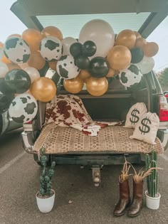 the back of a pickup truck decorated with balloons and cow print pillows, including a dollar sign