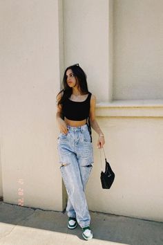 a woman leaning against a wall with her hand in her pocket