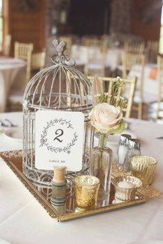 a birdcage filled with candles and flowers on top of a table