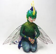 a green fairy sitting on the ground with her hands in her pockets and eyes closed