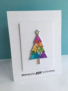 a card with a colorful christmas tree on the front, and words wishing you joy at christmas