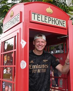 a man standing in a red phone booth