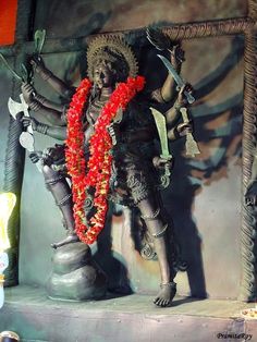 a statue with flowers around it in front of a wall