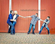 three people holding hands and standing in front of a red wall with two boys on it