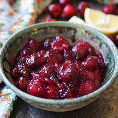 a bowl filled with cranberry sauce on top of a table next to sliced lemons