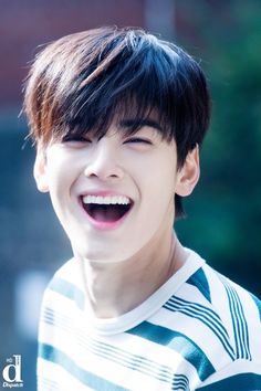 a young man smiling and wearing a striped shirt