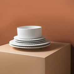 stack of plates sitting on top of each other in front of an orange wall with no one around them