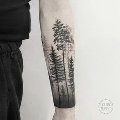 a man with a forest tattoo on his arm