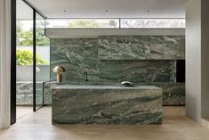 a modern kitchen with marble counter tops and an island in front of glass doors that lead to the outside