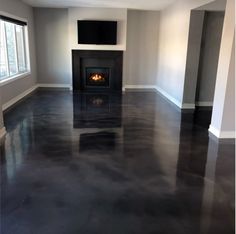 an empty living room with black floors and a fireplace