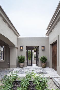 a courtyard with potted plants and two doors