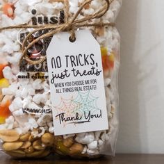 a bag filled with candy corn and halloween candies next to a sign that says, no tricks just treats when you choose me for all things real estate