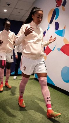 the girls are playing soccer on the green carpeted floor in front of a colorful wall