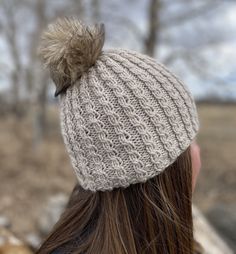 a woman wearing a knitted hat with a pom - pom