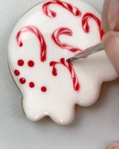 a person cutting into a decorated cookie with red and white icing