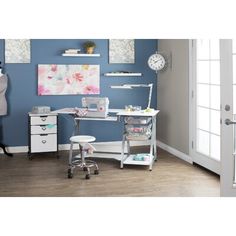 a room with blue walls and white furniture, including a sewing machine on the desk