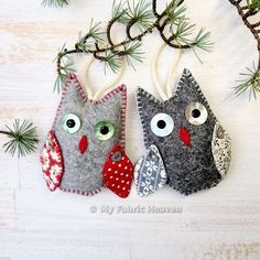 two felt owl ornaments hanging from a pine tree