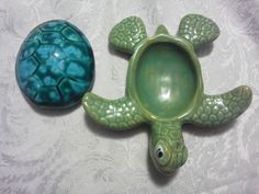 two green and blue turtle shaped dishes on a white tableclothed surface, one has an egg in it's shell