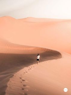 a person walking in the middle of a desert with footprints coming out of the sand