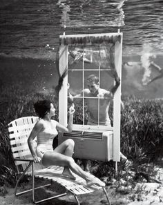 a woman sitting on a beach chair next to a cage with dogs in it, under water