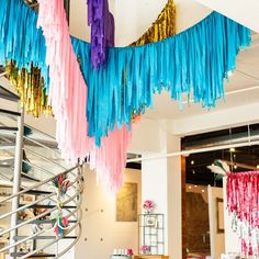 colorful streamers hanging from the ceiling in a room with white walls and metal railings