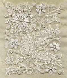 an embroidered white cloth with flowers and leaves on it