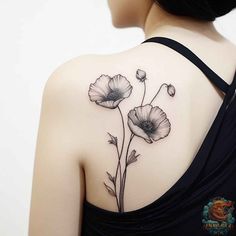 the back of a woman's shoulder with two flowers on her left arm and one flower